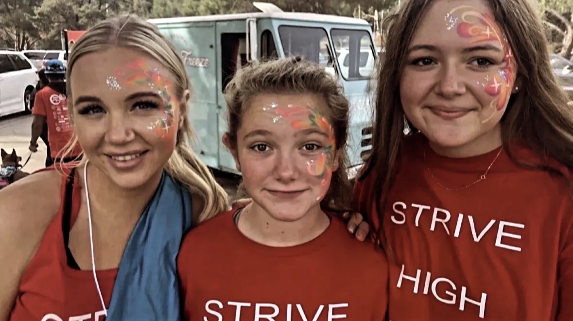 Three Strive High students with colorful face paint smiling on celebration day